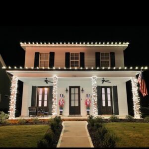 Southern style home with porch columns wrapped in Christmas lights and warm white roofline lighting