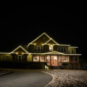 Large Georgia home glowing with warm white Christmas roofline lighting against a black night sky