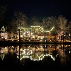 Lakefront Georgia estate covered in Christmas lights reflecting across the water at night